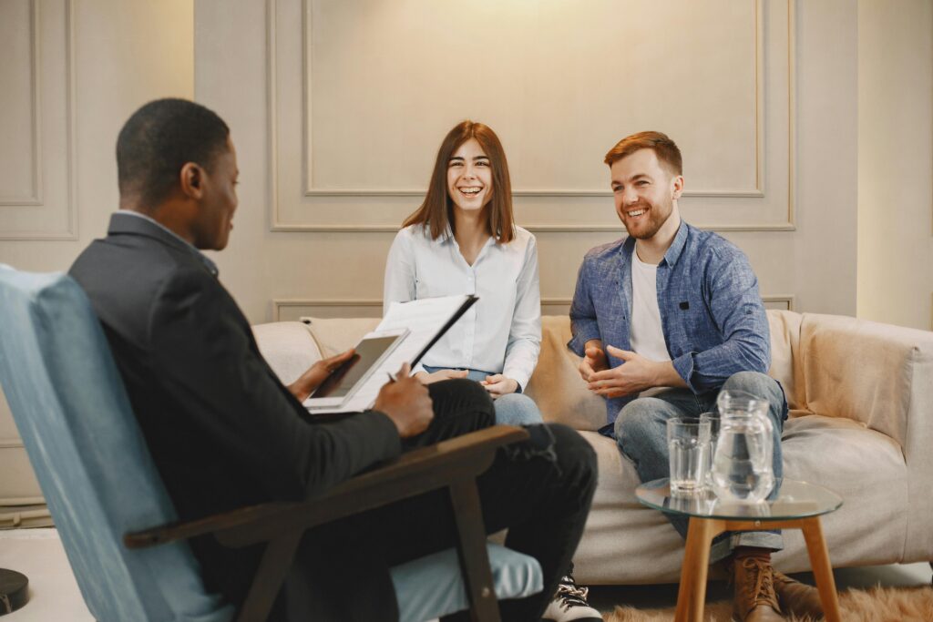 pexels-photo-7447256-7447256 A happy couple engages with an advisor during a consultation in a cozy living room.