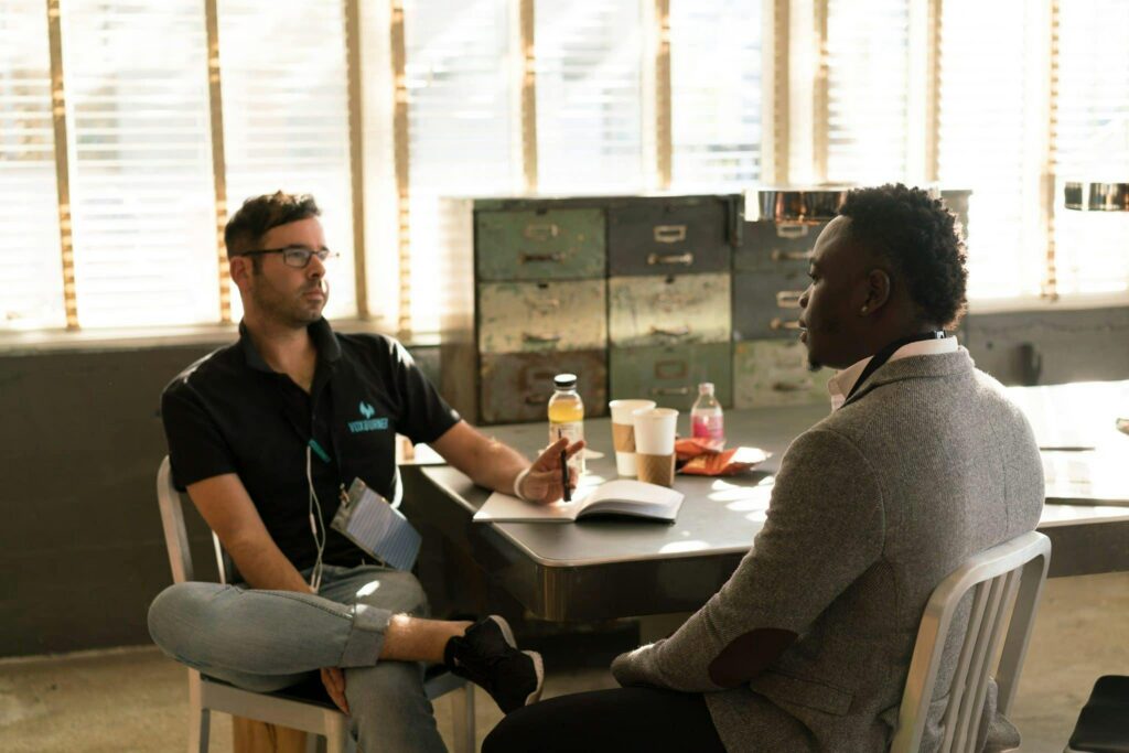 pexels-photo-935977-935977 Two men having a focused business discussion in a sunlit office space.