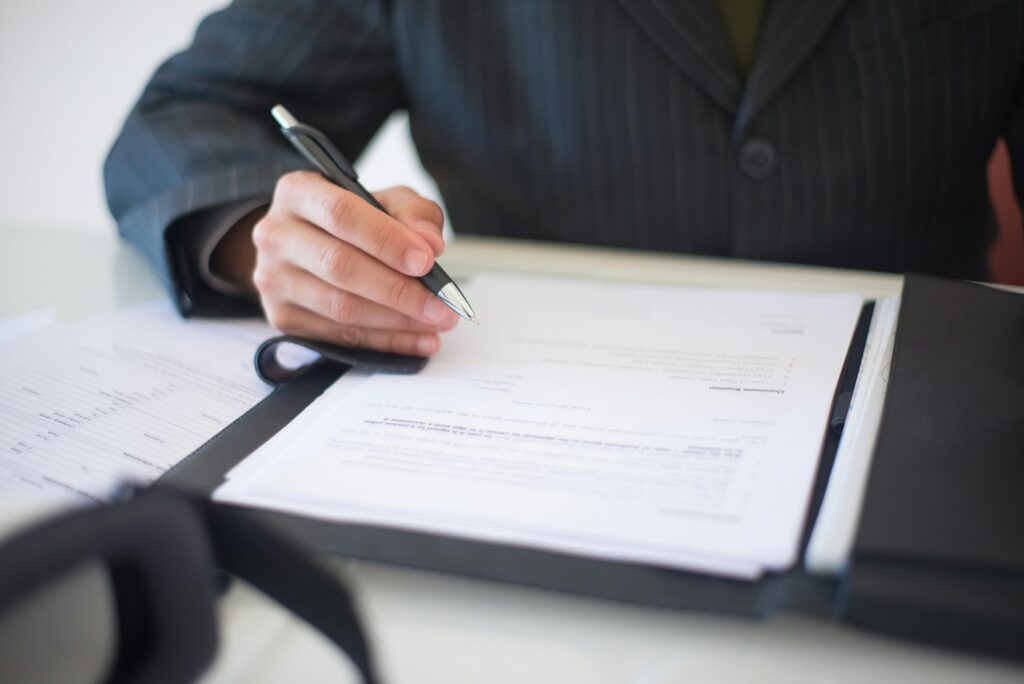 pexels-photo-8815849-8815849 Close-up of a hand signing documents with a pen, symbolizing an important business contract.